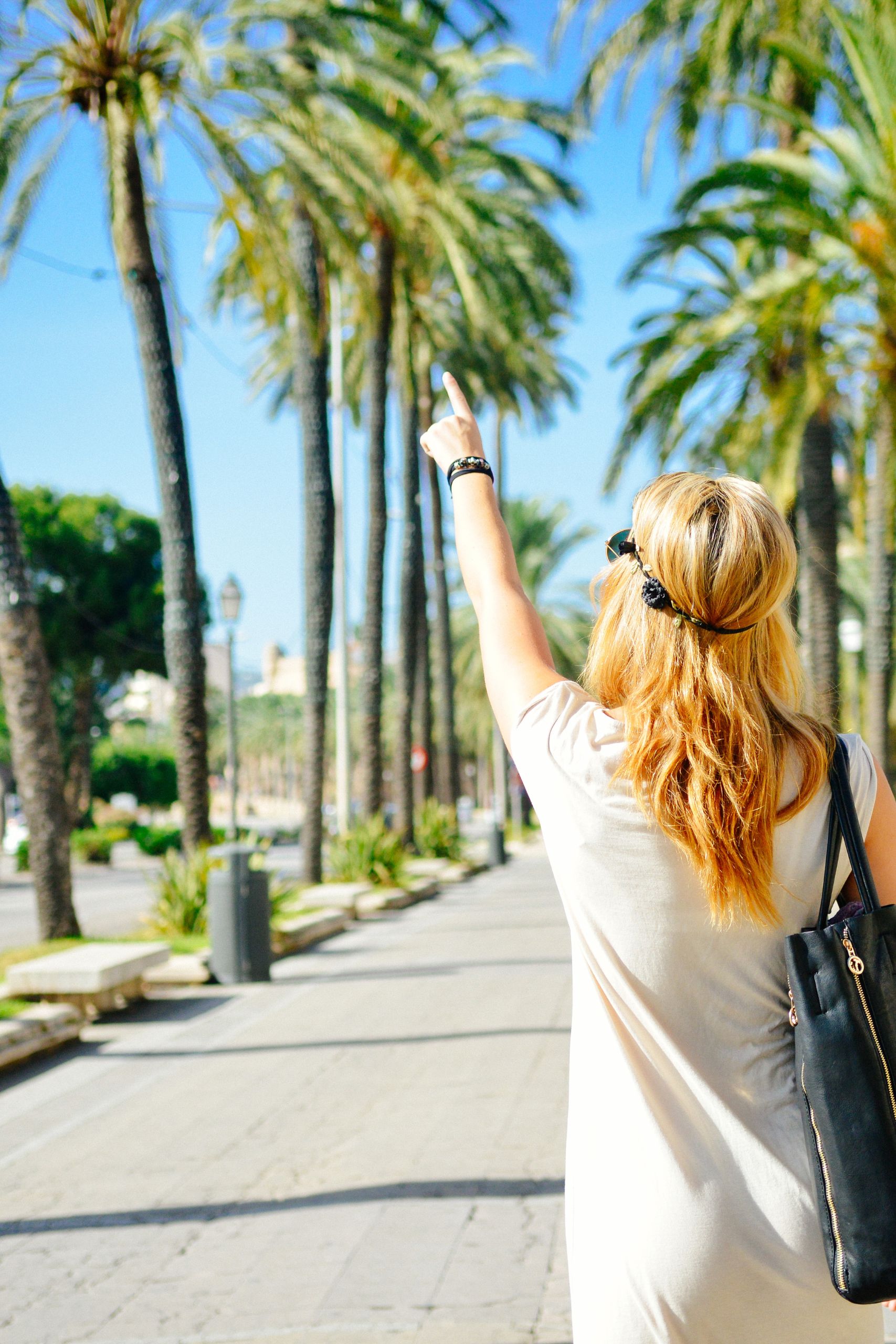 woman pointing with palm tress in front of her